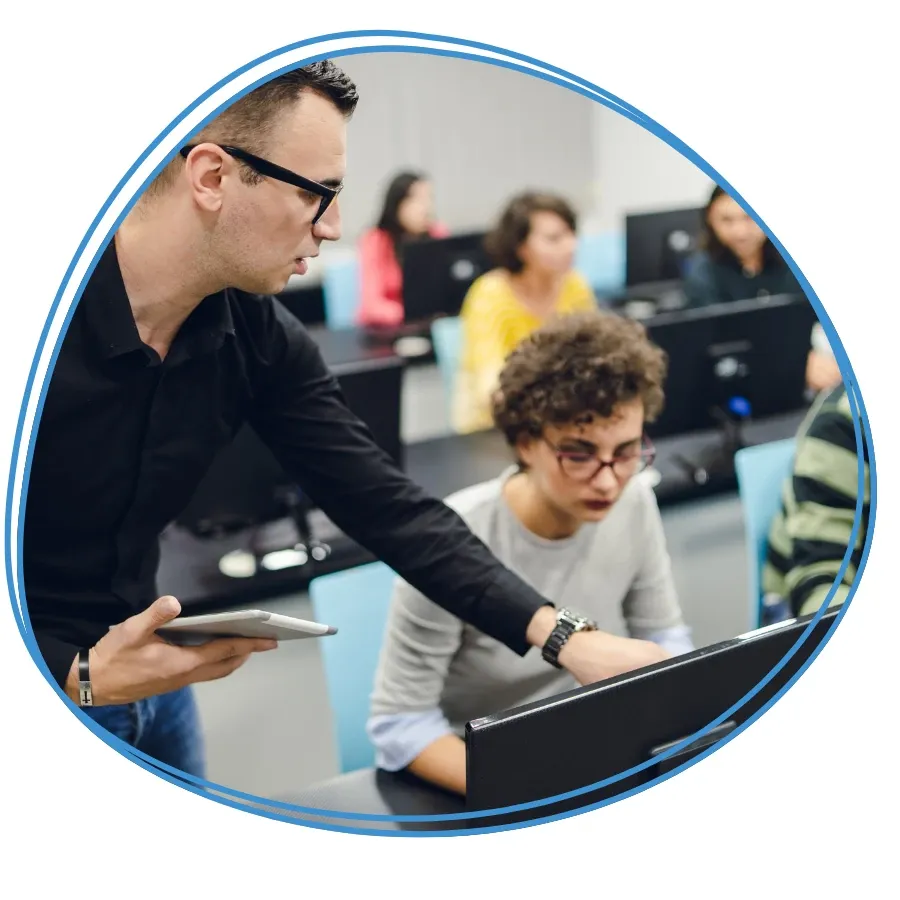 An instructor helping students at computers in a classroom