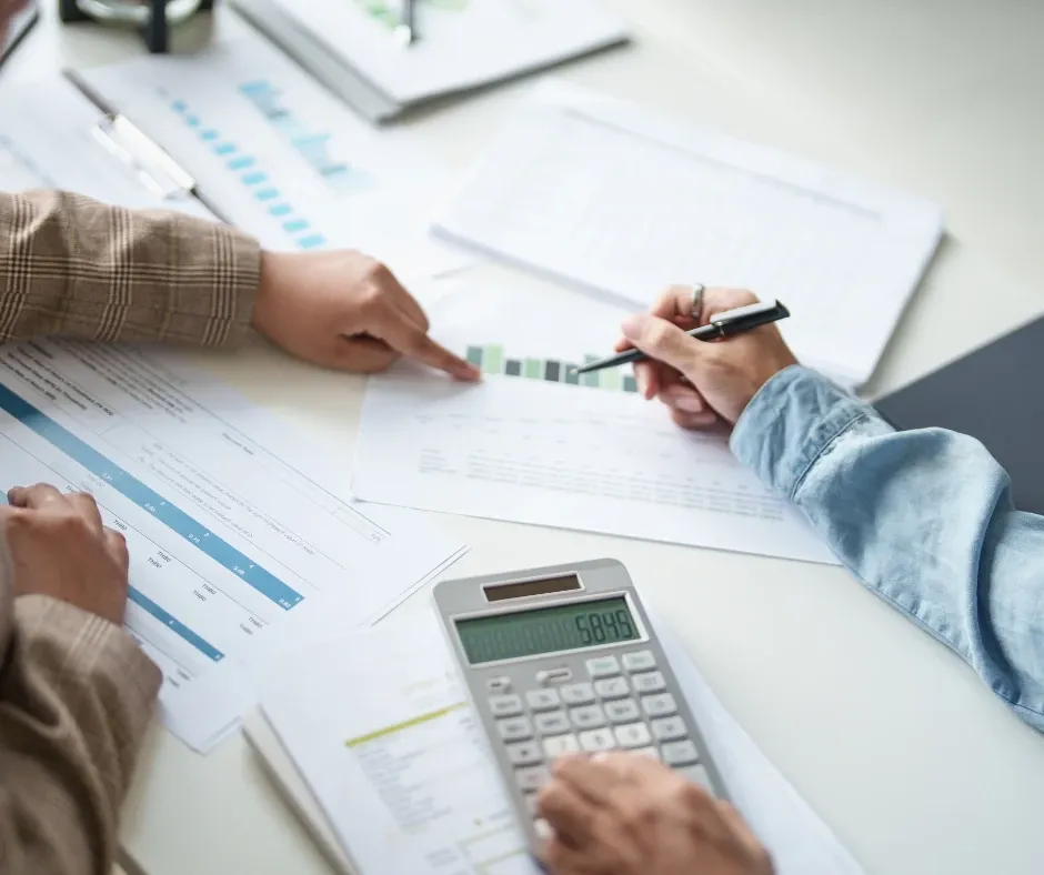 Hands reviewing financial reports with a calculator