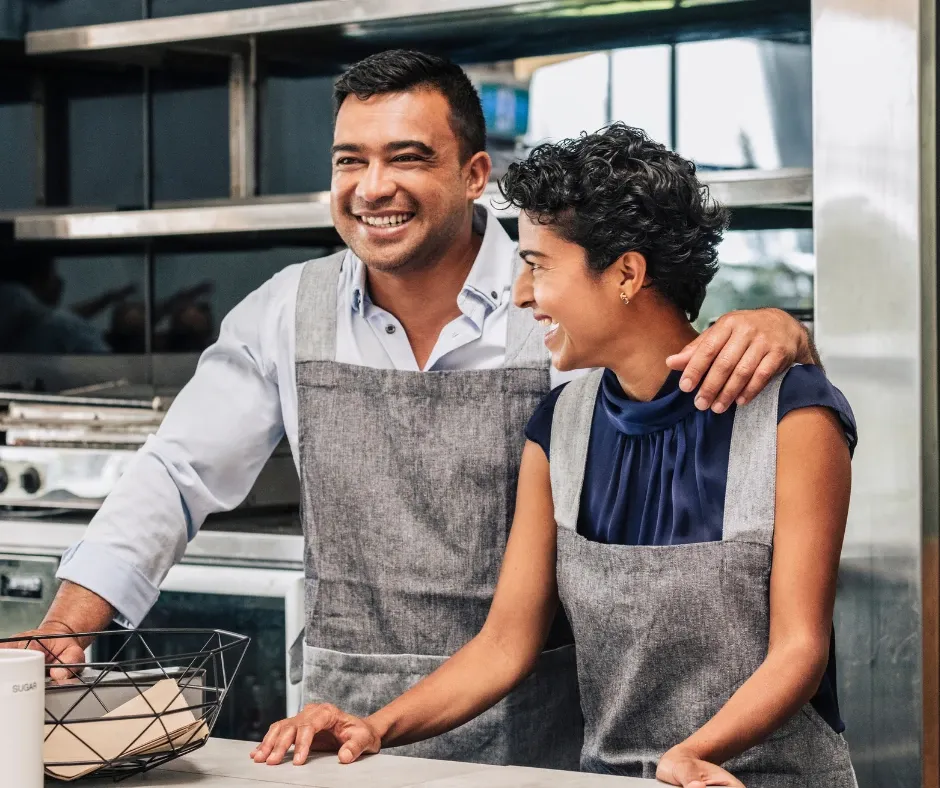 Two smiling small business owners in aprons